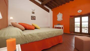 Un dormitorio con cama, mesita de noche, ventana y vistas al exterior.