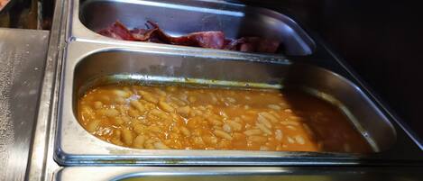 A buffet with various food options including pasta, scrambled eggs, and bacon.