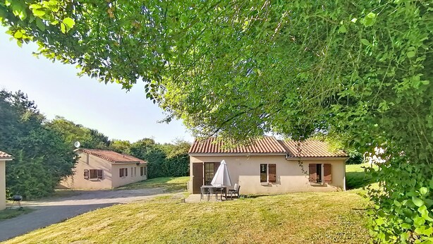 Un área residencial con dos casas, una de techo a dos aguas y otra con techo plano, ambas con ventanas y puertas a la vista.