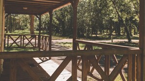 Un pabellón de madera con estructura de techo en forma de cruz, rodeado de un área boscosa.