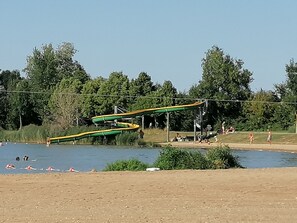 A water park with a lazy river, green and yellow slides, and a sandy beach area. - Terres de France - Moncontour Active Park (Moncontour)