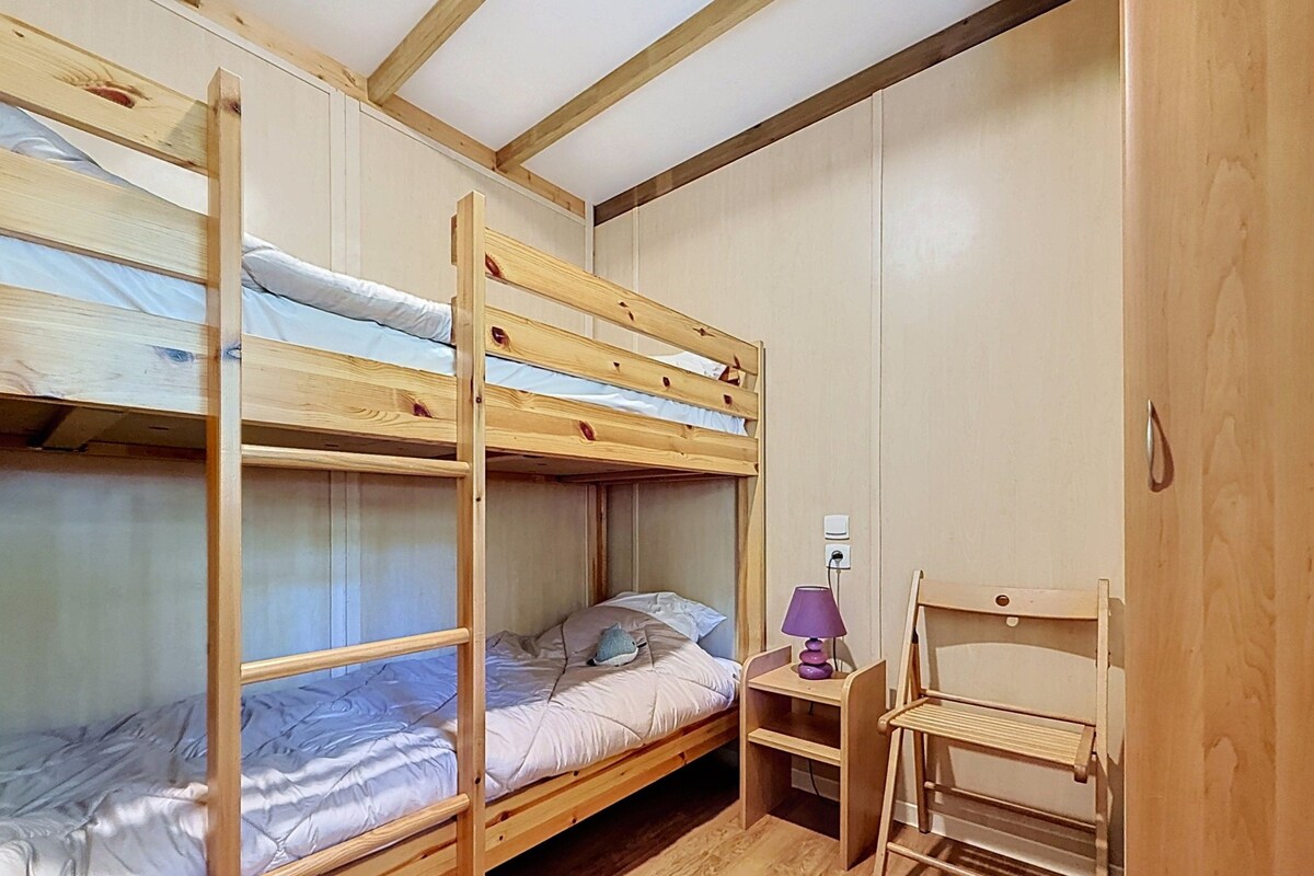 Une chambre avec un lit superposé, un bureau et une chaise, une lampe et une armoire.