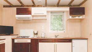 Una cocina compacta con armarios de madera, estufa integrada, pileta y ventana con persianas.
