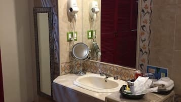Un baño con lavamanos, espejo, secador de pelo y toallero.