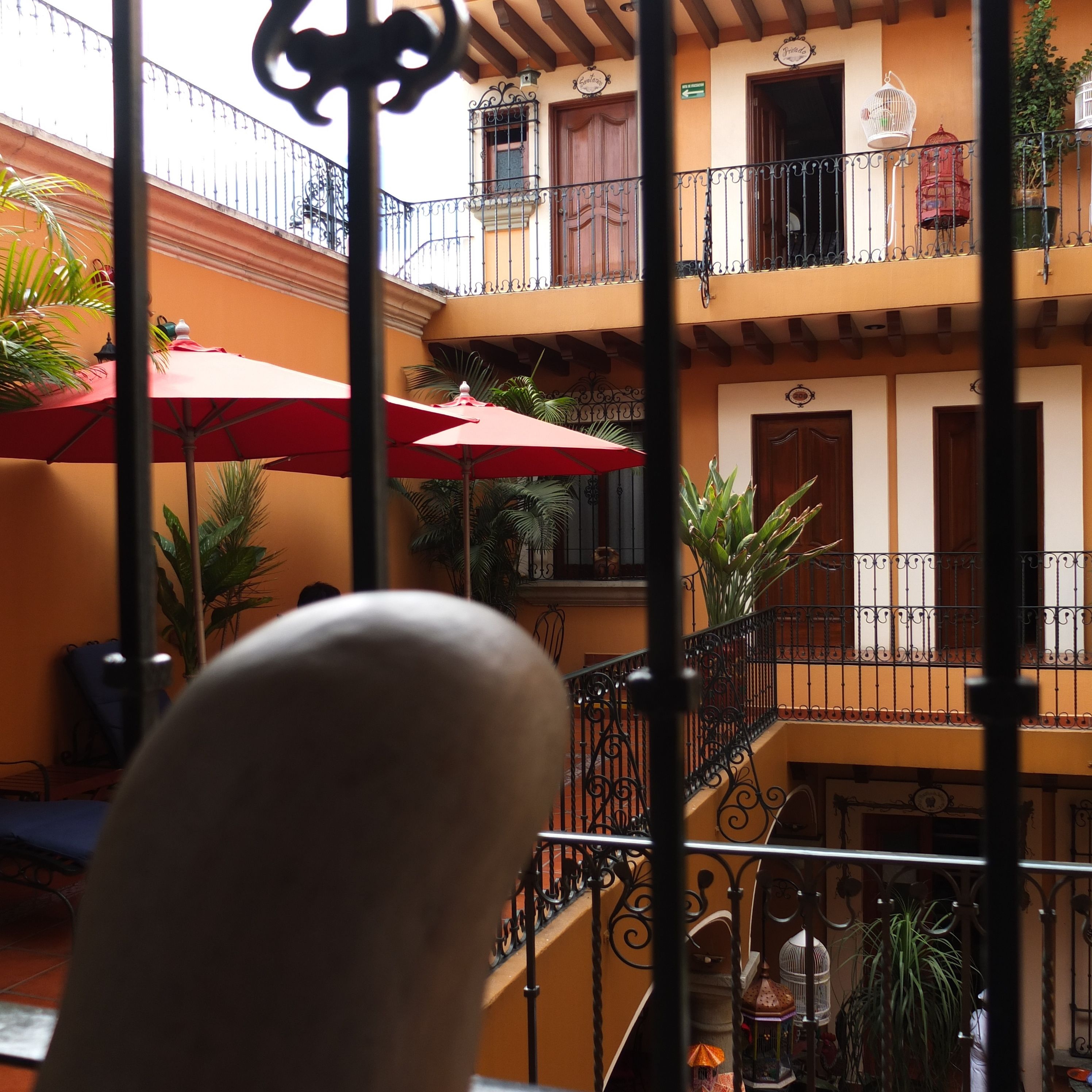 A courtyard with a red umbrella, potted plants, and a staircase leading to a balcony.