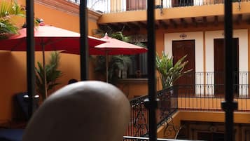 A courtyard with a red umbrella, potted plants, and a staircase leading to a balcony.