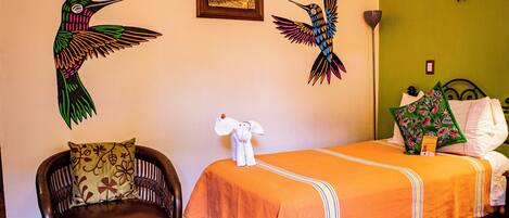 A hotel room with a bed, a chair, and two wall-mounted wall art pieces.