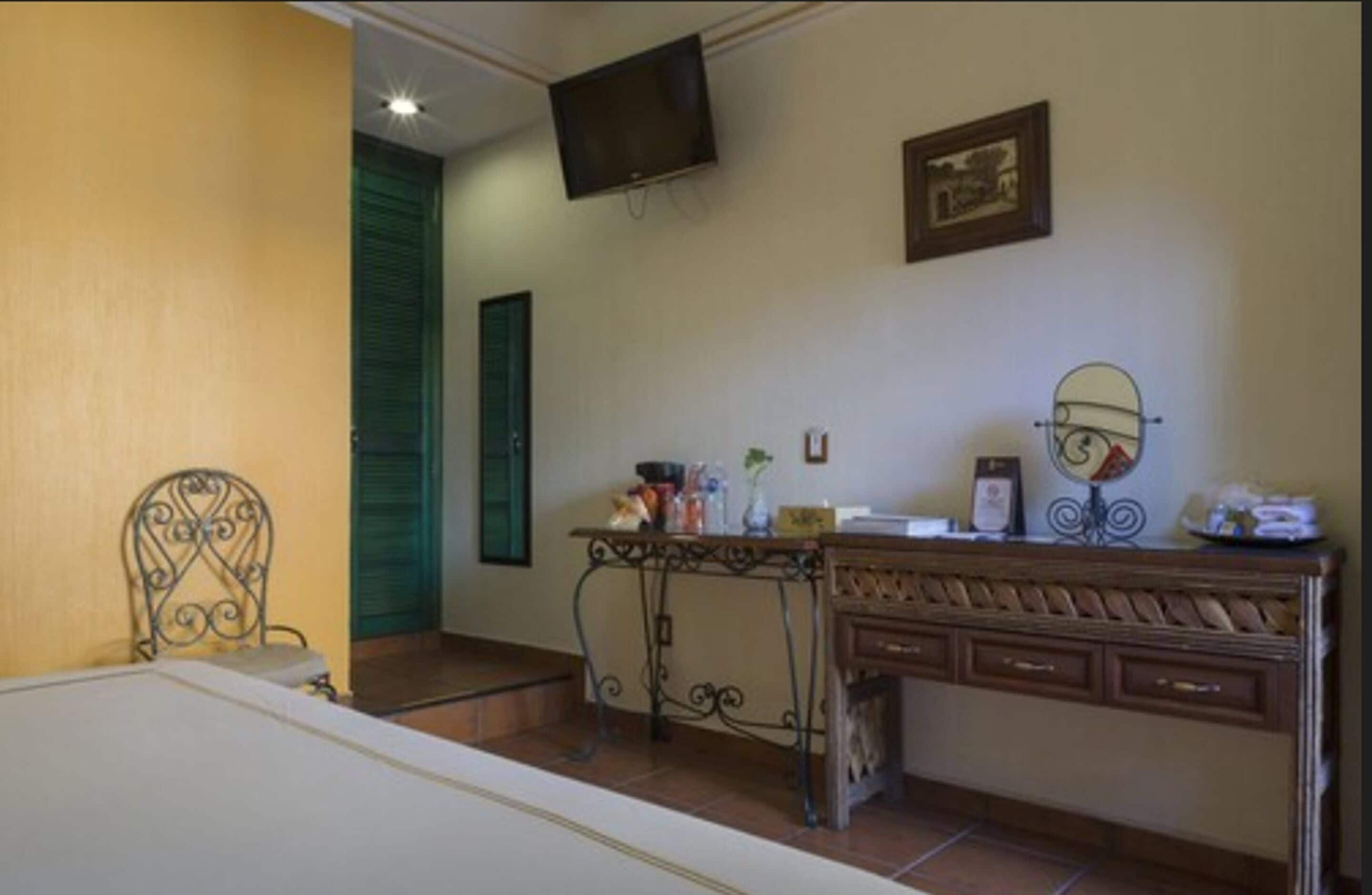 A bedroom with a bed, a desk, a chair, a television, and a dresser.