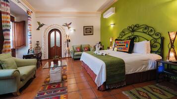 Habitación de hotel con cama, sofá, una mesita, un muro decorativo y una ventana con cortinas.