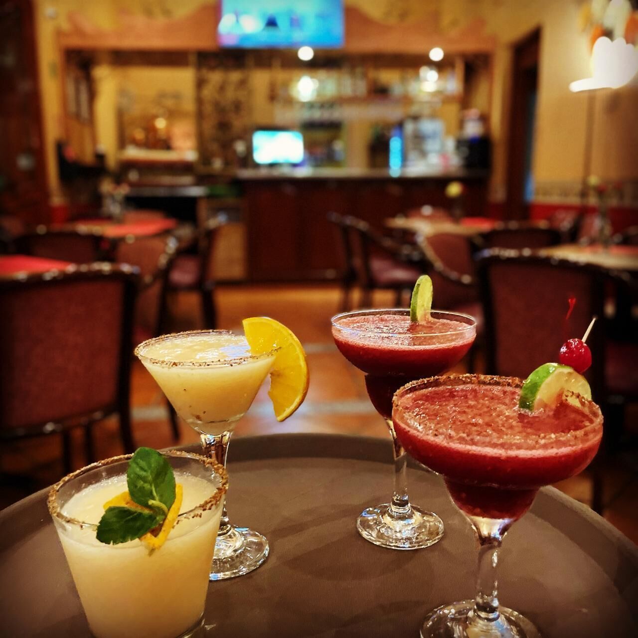 A bar area with three cocktails on a table.