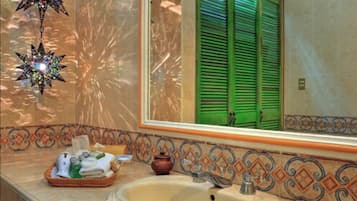 Een badkamer met een wastafel, groene luiken, decoratieve tegels en een stervormige versiering.