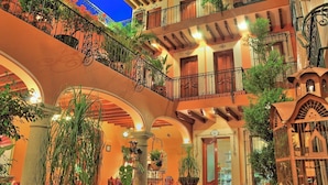 Un hôtel à plusieurs étages doté de balcons, d’arcades et de plantes en pot.