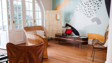 A room with wicker furniture, a piano, and a wall mural.