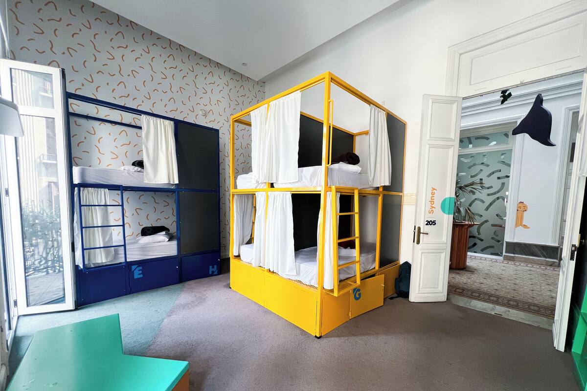 A room with bunk beds, a desk, and a door labeled "Sydney 205".