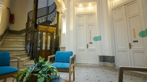 A hotel lobby with a staircase, two blue armchairs, a potted plant, and doors labeled "Helsinki" and "201". - Viajero Montevideo Hostel (Montevideo)