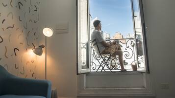 Una habitación con un ventanal grande, una silla, una lámpara y un radiador.