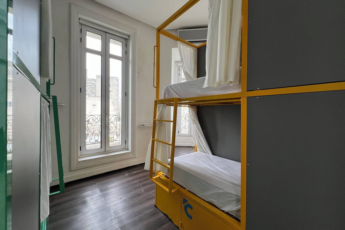 A bunk bed room with a window and a door.