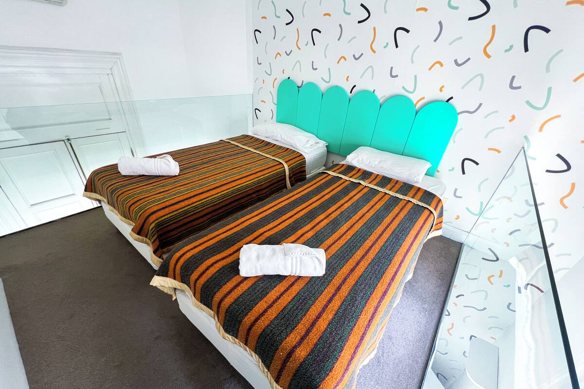 A hotel room with two beds, each with striped bedding and white towels.
