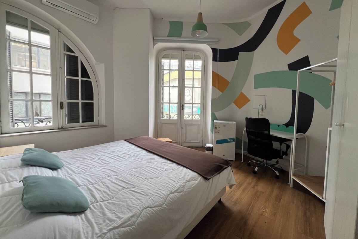 A bedroom with a bed, a desk, and a chair.