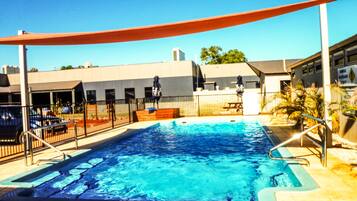 Relax by the pool surrounded by a deck and lounge chairs, with a shaded area under a large canopy.