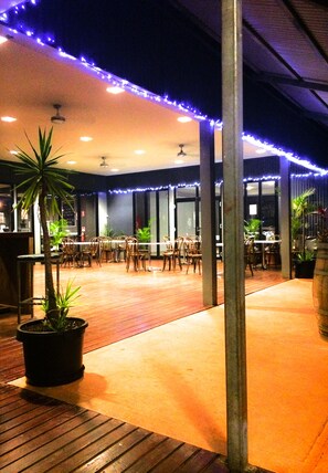 An outdoor dining area with wooden flooring, tables, chairs, and potted plants. - Spinifex Hotel (Derby)