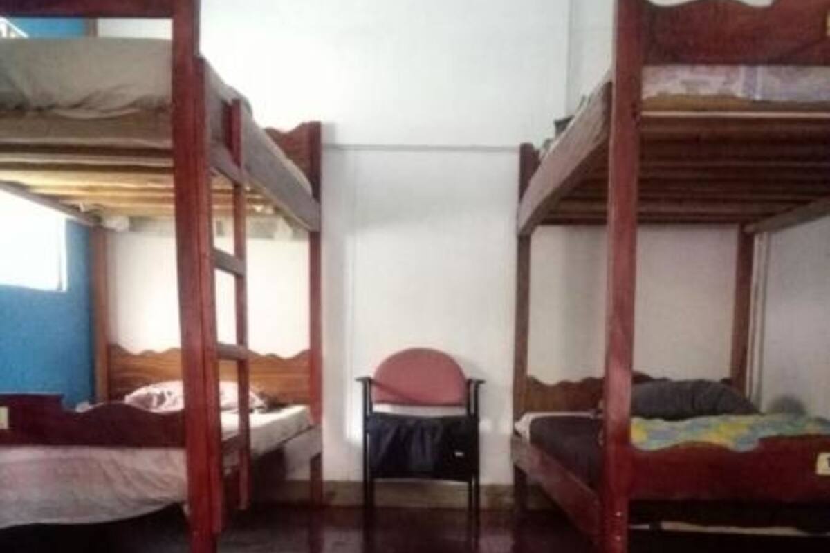 Quarto com beliches, uma cadeira e uma janela.