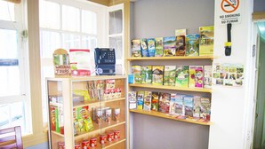 Una stanza con un armadietto in legno pieno di snack e una macchina del caffè. Si vedono scaffali con libri e un cartello che indica divieto di fumare.