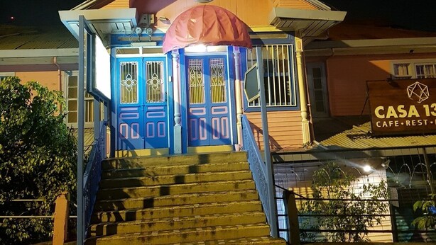 Un edificio con facciata blu, tetto rosso e una scalinata che conduce all'ingresso.