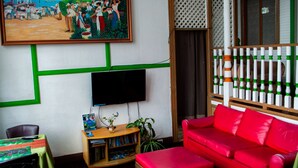 Un soggiorno con un divano rosso, una TV a schermo piatto, una libreria e un quadro appeso al muro.