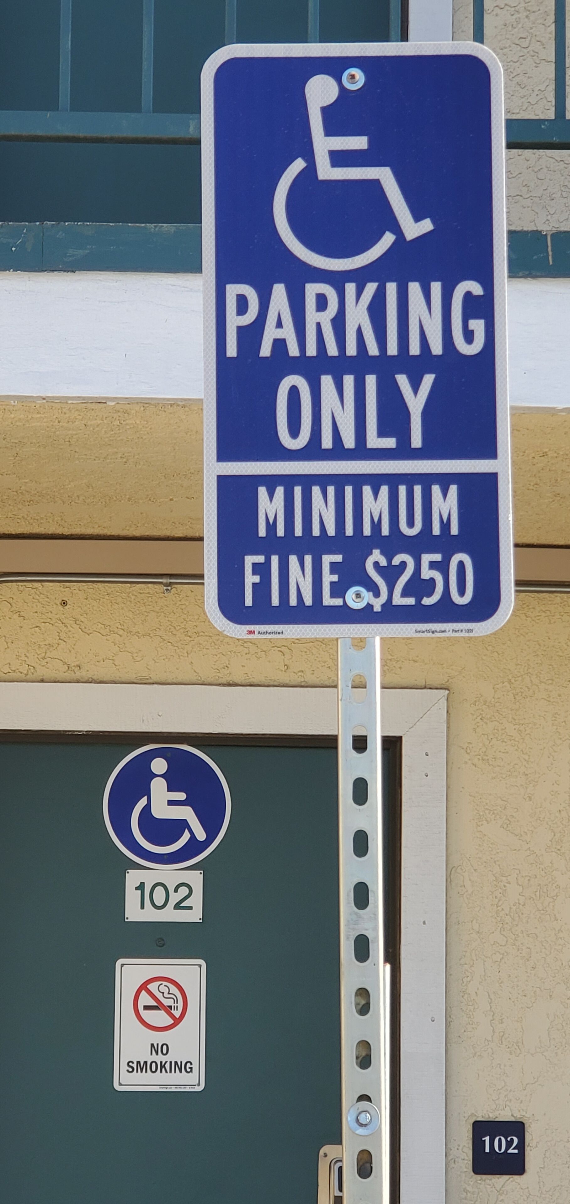 A parking sign indicating reserved parking for disabled individuals with a minimum fine of $250.