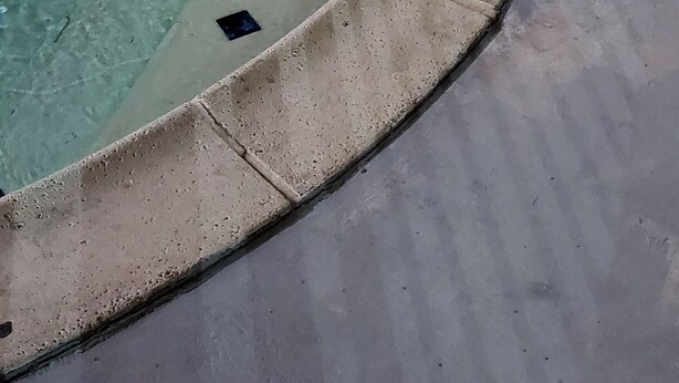 Piscina com guarda-corpo de metal e borda revestida em azulejo.