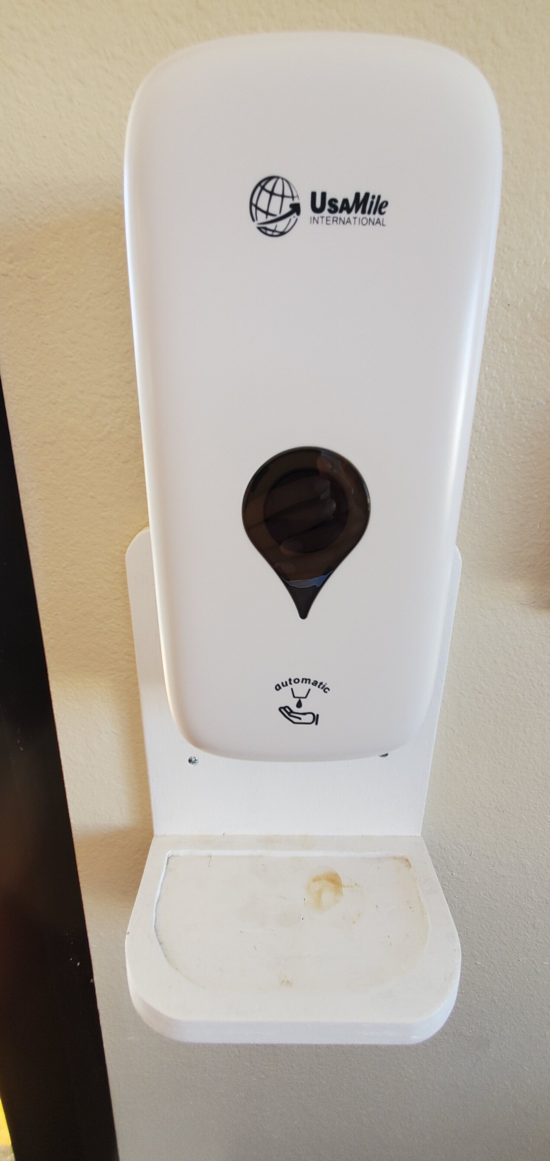 A white hand sanitizer dispenser with the logo "UsaMile International" and the word "aromatic" below it.