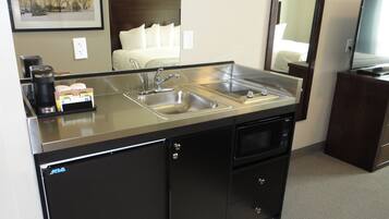 Cocina de hotel compacta con un lavamanos doble, cafetera y microondas.