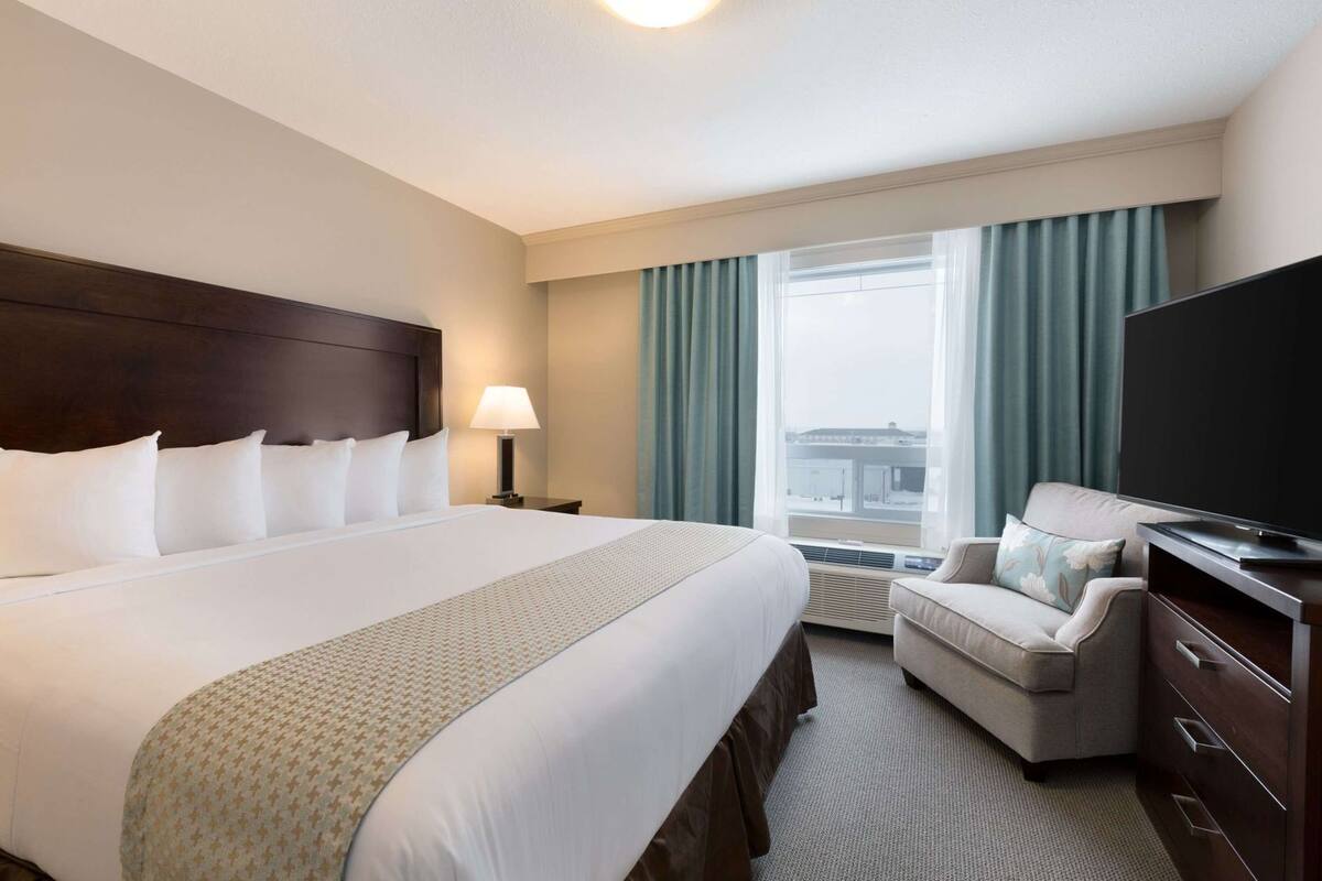 A hotel room with a large bed, a TV, a desk, and a chair.