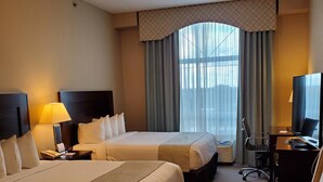 A hotel room with two beds, a desk, a chair, and a television. - Ramada by Wyndham Emerald Park/Regina East (Emerald Park)