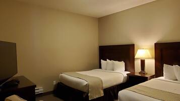 A hotel room with two beds, a TV, a lamp, and a sofa.