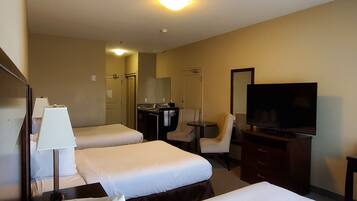 Habitación de hotel con dos camas, un escritorio, una silla, un televisor y un espejo.