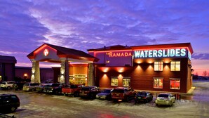 A hotel with a 'WATERSLIDES' sign, a 'RAMADA' sign, and a gas station with a red canopy. - Ramada by Wyndham Emerald Park/Regina East (Emerald Park)