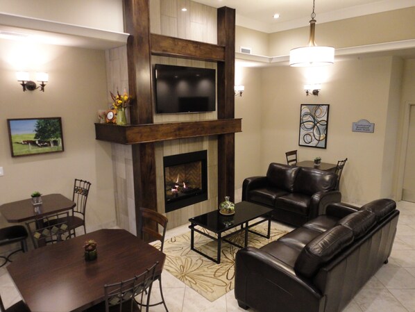 A living room with a fireplace, a television, a sofa, and a dining area.
