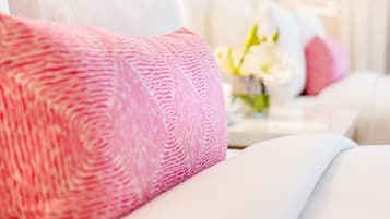 A neatly made bed with a pink textured blanket and a white pillow.