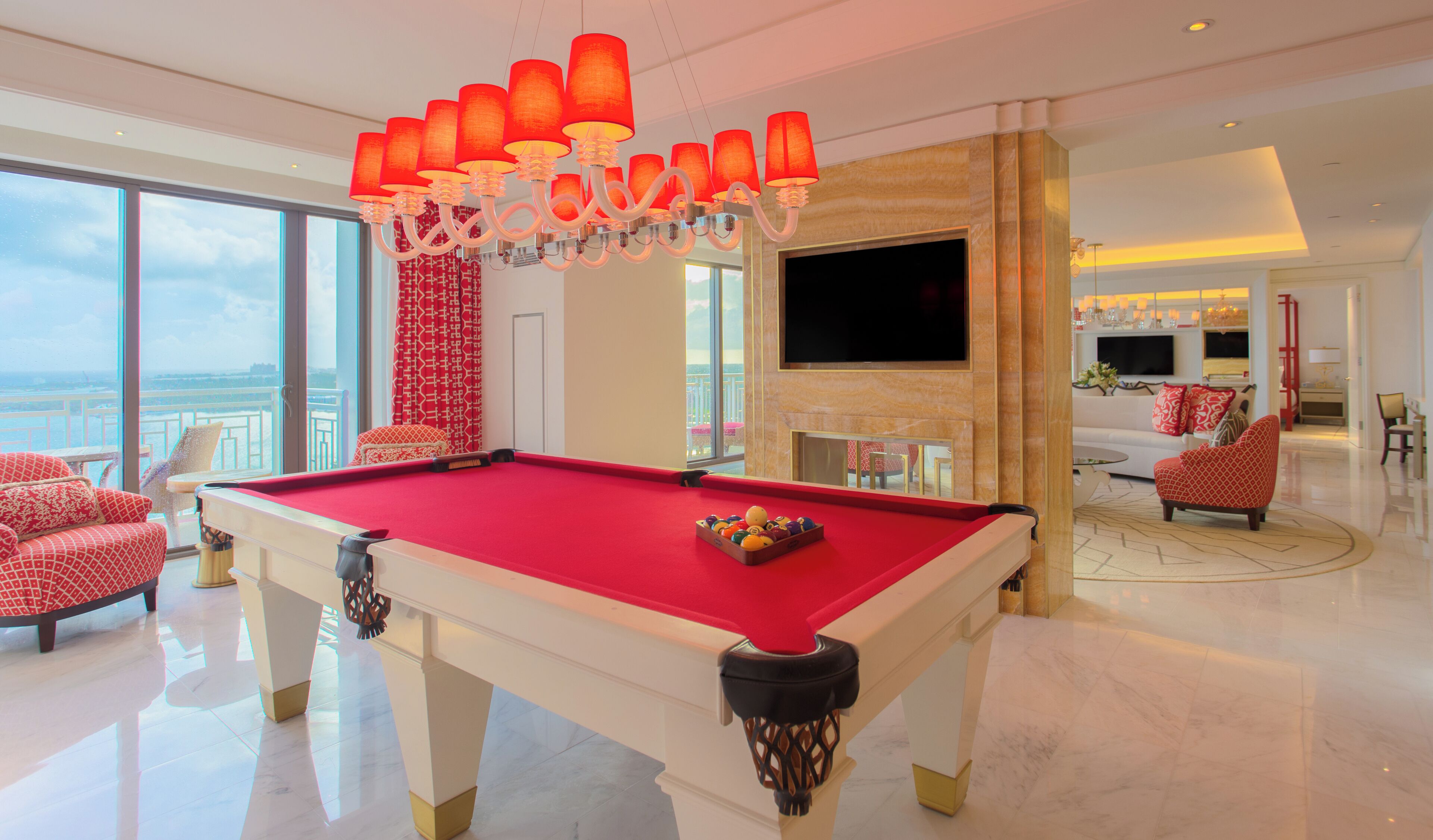 A spacious living area with a pool table, a large TV, and a balcony with a view.