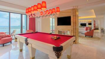 A spacious living area with a pool table, a large TV, and a balcony with a view.