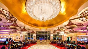A luxurious hotel lobby with a grand chandelier, multiple gaming tables, and a large window in the background. - Grand Hyatt Baha Mar (Nassau)
