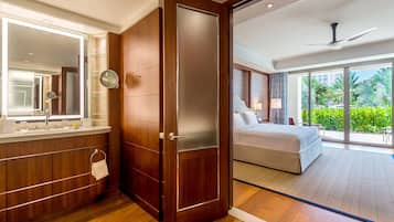 Une chambre d’hôtel moderne dotée d’une coiffeuse en bois, d’un grand miroir, d’un lit donnant sur l’extérieur et d’un ventilateur de plafond.