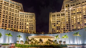 A hotel with a modern design, featuring a large central courtyard with palm trees and a fountain.