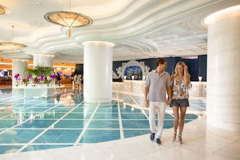 A spacious, well-lit hallway with a high ceiling, featuring a central chandelier and flanked by potted palm trees. at Grand Hyatt Baha Mar
