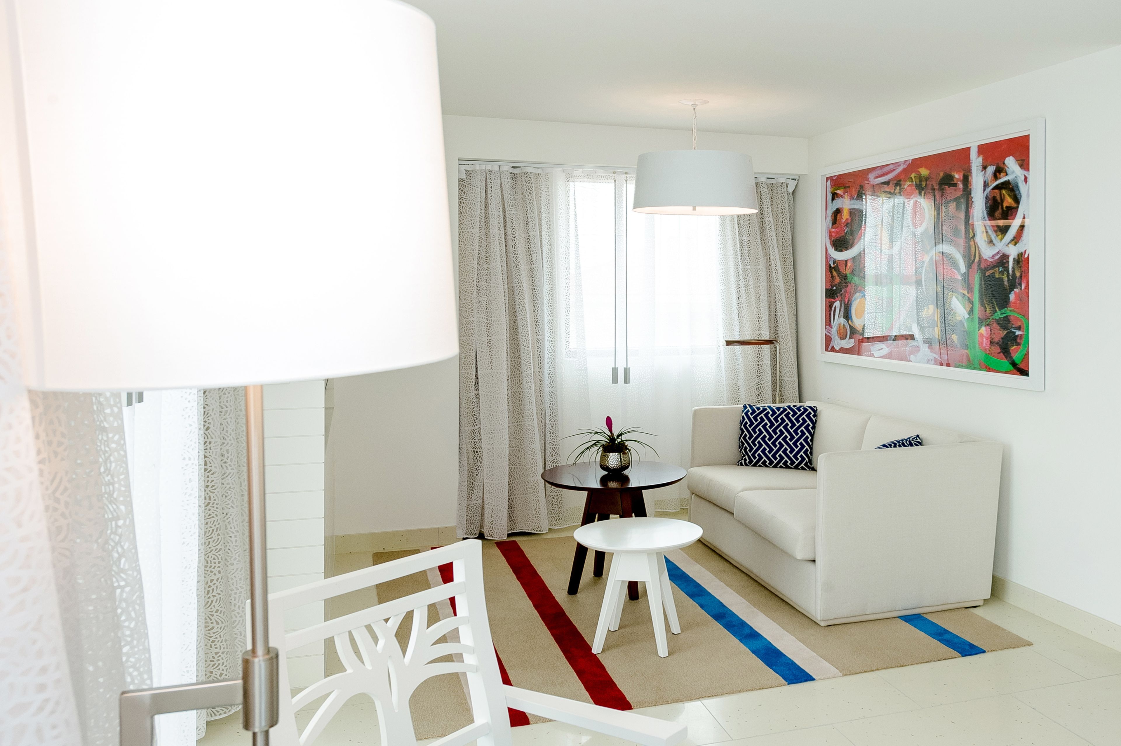 A modern living room with a white sofa, a small round table, and a lamp.