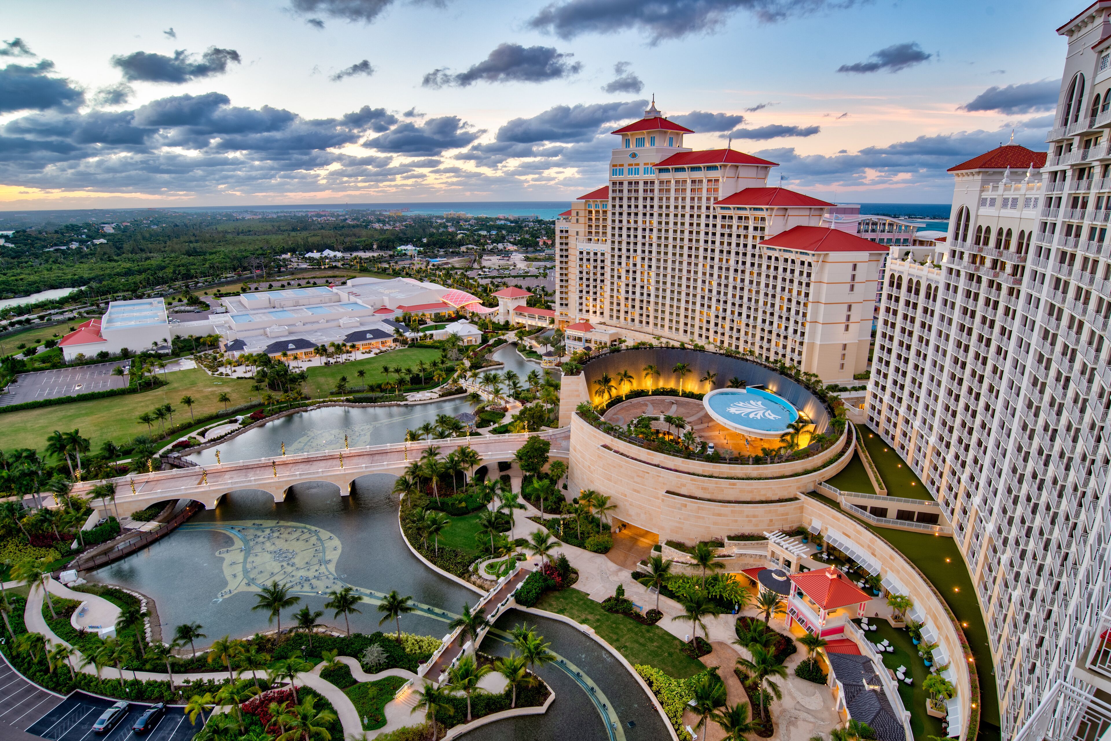 A hotel with multiple high-rise buildings, a central courtyard with a pool, and surrounding greenery.