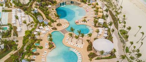 A resort with multiple swimming pools, sun loungers, and palm trees.