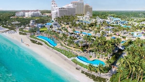 A resort with a beach, multiple swimming pools, and a variety of buildings.